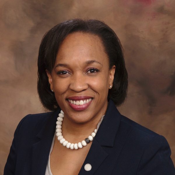 A headshot of Valerie Williams-Sanchez against a watercolor brown background.