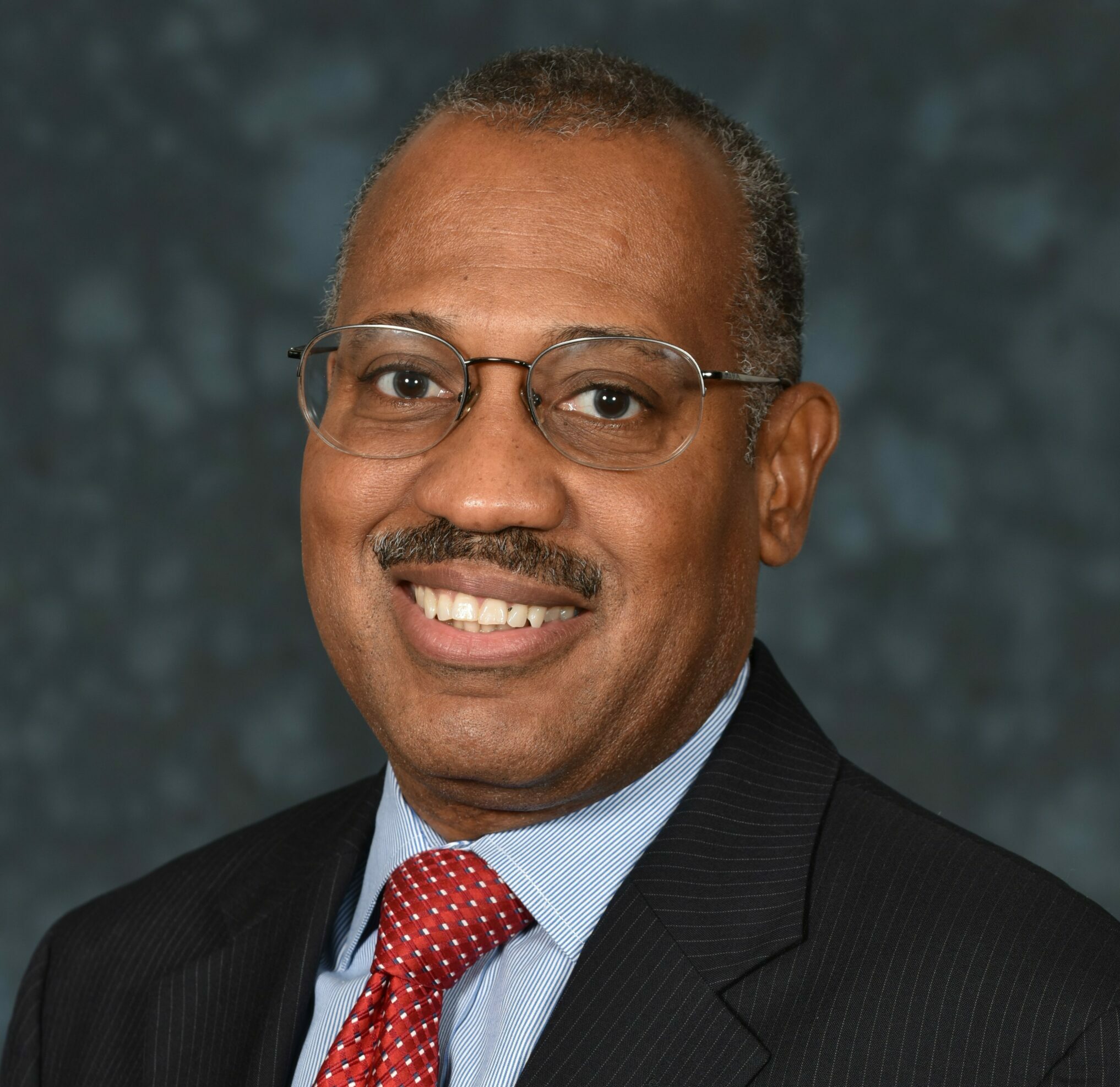 A headshot of Jon Walls against a watercolor grey background.